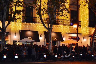 People on illuminated street amidst buildings in city at night