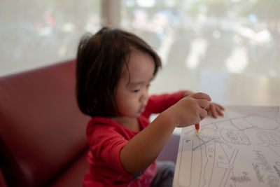 Side view of baby girl drawing on paper