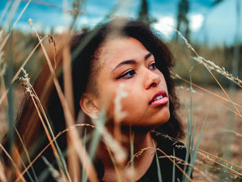 Portrait of young woman looking away on field