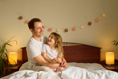 Young couple sitting on bed at home