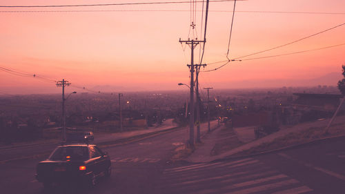 Vehicles on road against sky during sunset