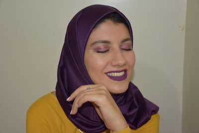 Portrait of smiling young woman against wall