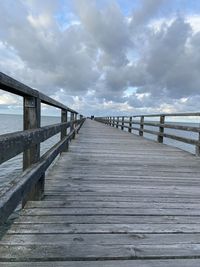 Wooden pier over sea against sky