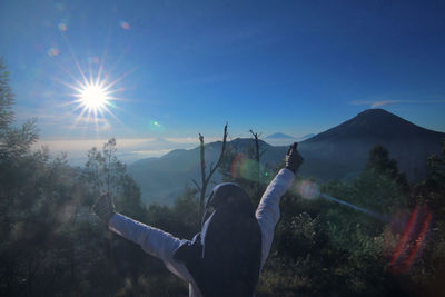 Rear view of woman with arms raised against sky