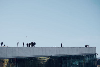 People on bridge against clear blue sky