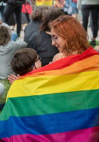 Rear view of siblings, wrapped up into lgbt flag