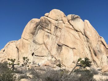 Low angle view of rock formation against clear blue sky