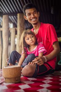 Portrait of happy mother and daughter sitting on floor