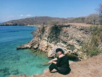 Full length of woman sitting on rock against sky