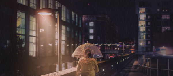 Rear view of people walking on street in rain