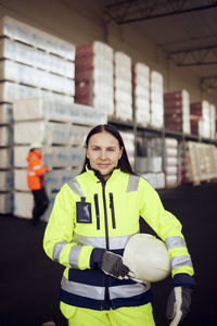 Portrait of smiling female blue-collar worker in protective workwear at industry