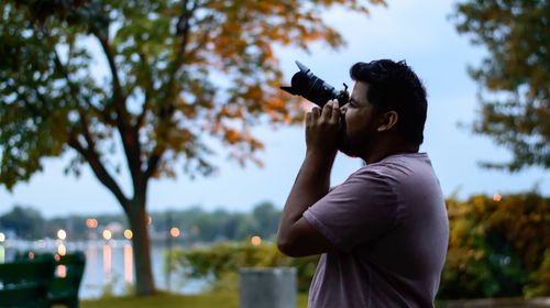 Side view of man photographing using camera