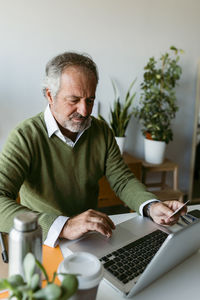 Mature man using credit card while working on laptop at home