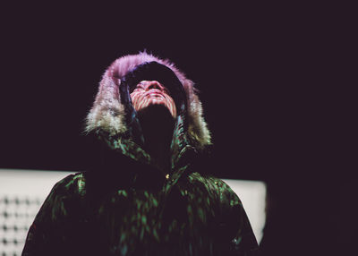 Man in fur coat looking up against wall