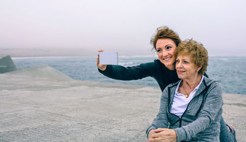 Portrait of smiling woman photographing while standing on beach