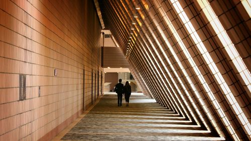 Full length rear view of man and woman walking in building corridor