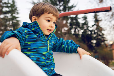 Cute boy playing on slide at playground