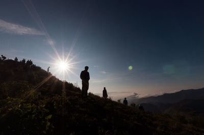 Silhouette people on mountain against sky