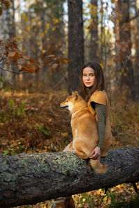 Beautiful woman walking shiba inu dog in fall forest. autumn mood