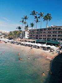 People swimming in pool by sea against sky