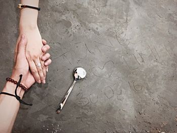 Cropped image of couple holding hands by text at beach