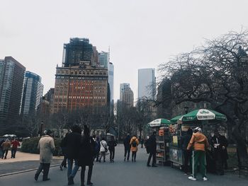 People walking in city against clear sky