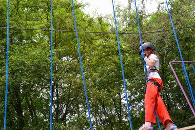 Adventure climbing high wire park - people on course in mountain helmet and safety equipment.