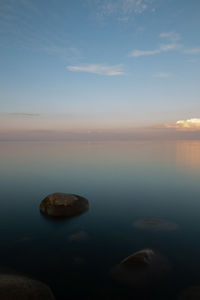 Rocks in sea against sky during sunset