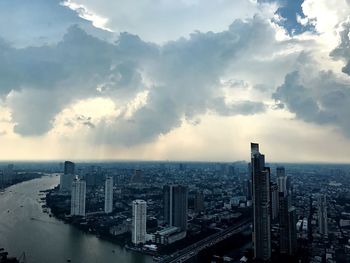 Aerial view of cityscape against cloudy sky