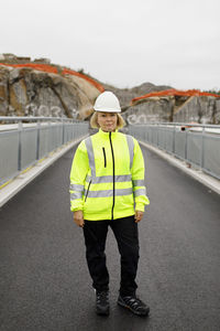 Portrait of female engineer in reflecting clothing standing on bridge