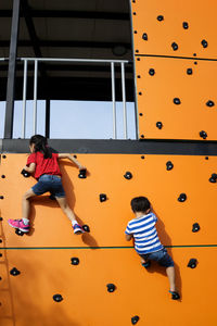 Low angle view of children climbing wall
