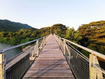 Footbridge leading to mountains against sky