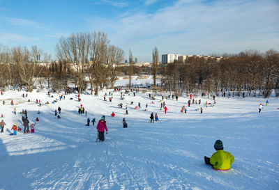 People on snowy field against sky during winter