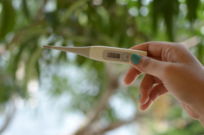 Close-up of woman hand holding thermometer