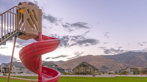Red flag on house by mountains against sky