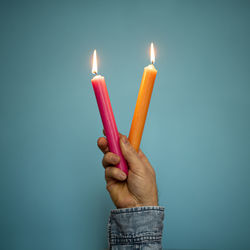 Hand holding two burning candles 