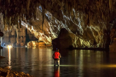 Rear view of woman standing on rock in cave