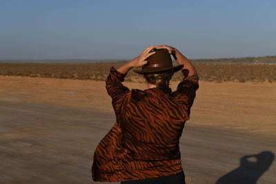 Midsection of woman standing in desert against sky