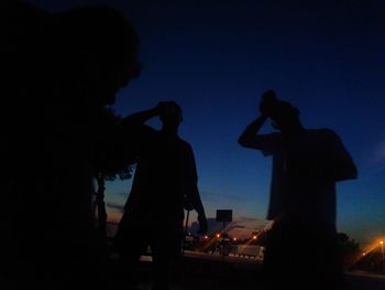 Silhouette people at music concert against sky at night