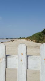 Wooden fence at sandy beach against clear sky