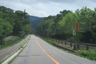 Road by trees against sky