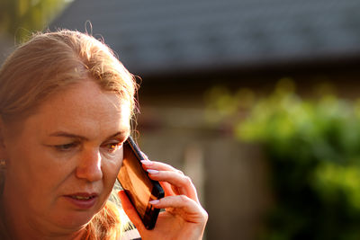 Closeup shot of a woman engaged in a serious phone talk outside. she is receiving upsetting news