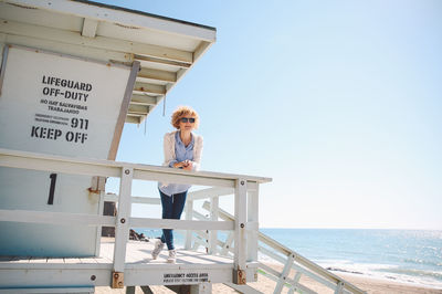 Woman standing by sea against clear sky