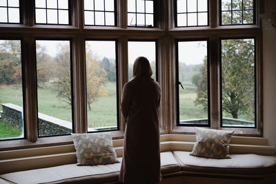 Rear view of woman looking through window