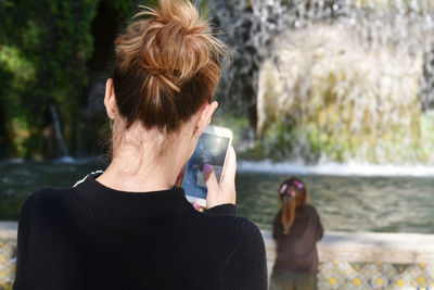 Full length rear view of woman drinking water from lake