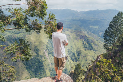 Rear view of woman standing on mountain against sky