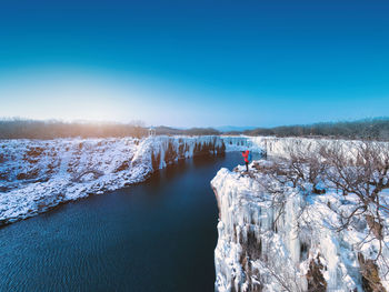 Scenic view of frozen lake against clear blue sky