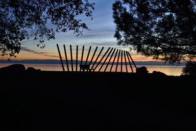 Silhouette tree by lake against sky at sunset