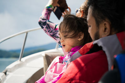 Cute girl with father sitting on boat