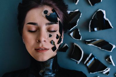 Close-up portrait of a beautiful young woman with broken glass and ceramics around her